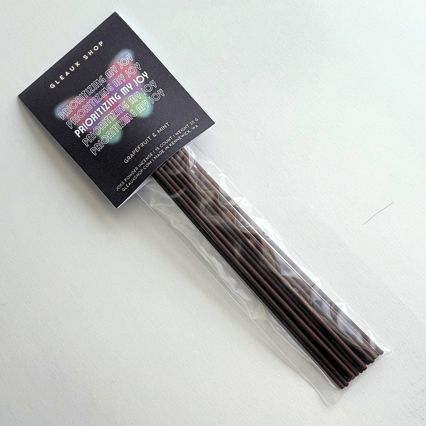 A pack of incense sticks with grapefruit and mint scent, displayed in front of its packaging that reads 'Prioritizing My Joy'.