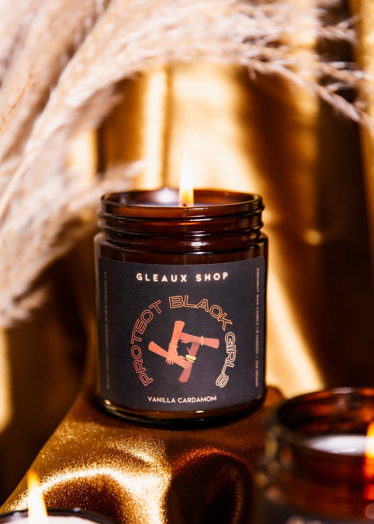 Gleaux Shop's Protect Black Girls vanilla cardamom scented candle in amber glass
